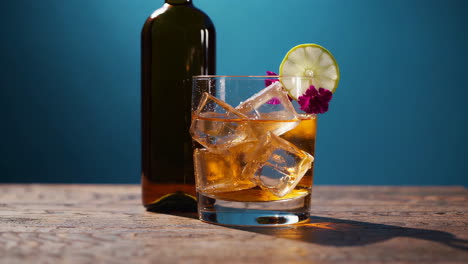 whiskey cocktail with ice and lime garnish on a wooden table