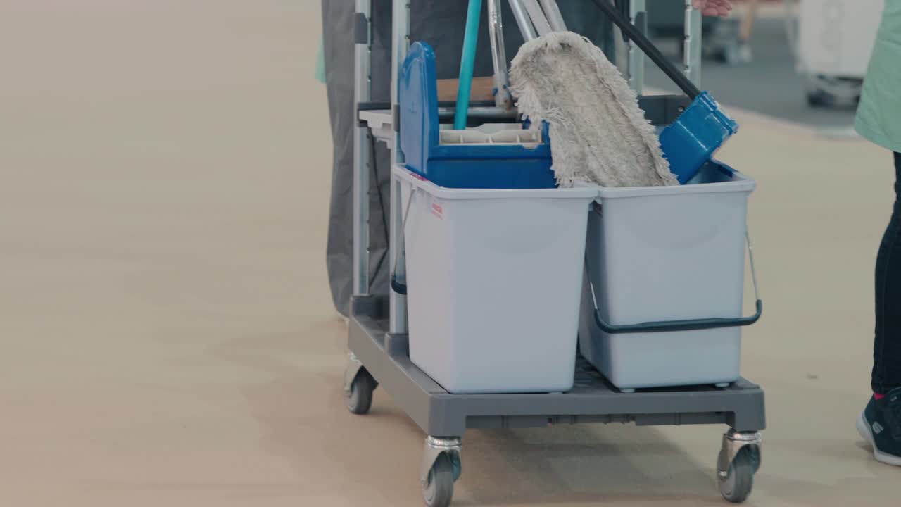 Janitorial cart with mops and cleaning supplies in facility corridor