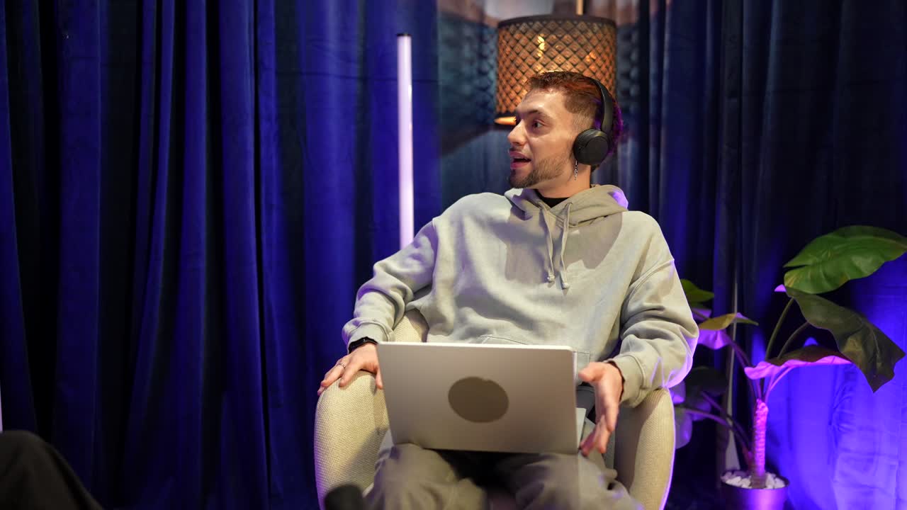 Mladý muž ve sluchátkách mluví a gestikuluje s notebookem