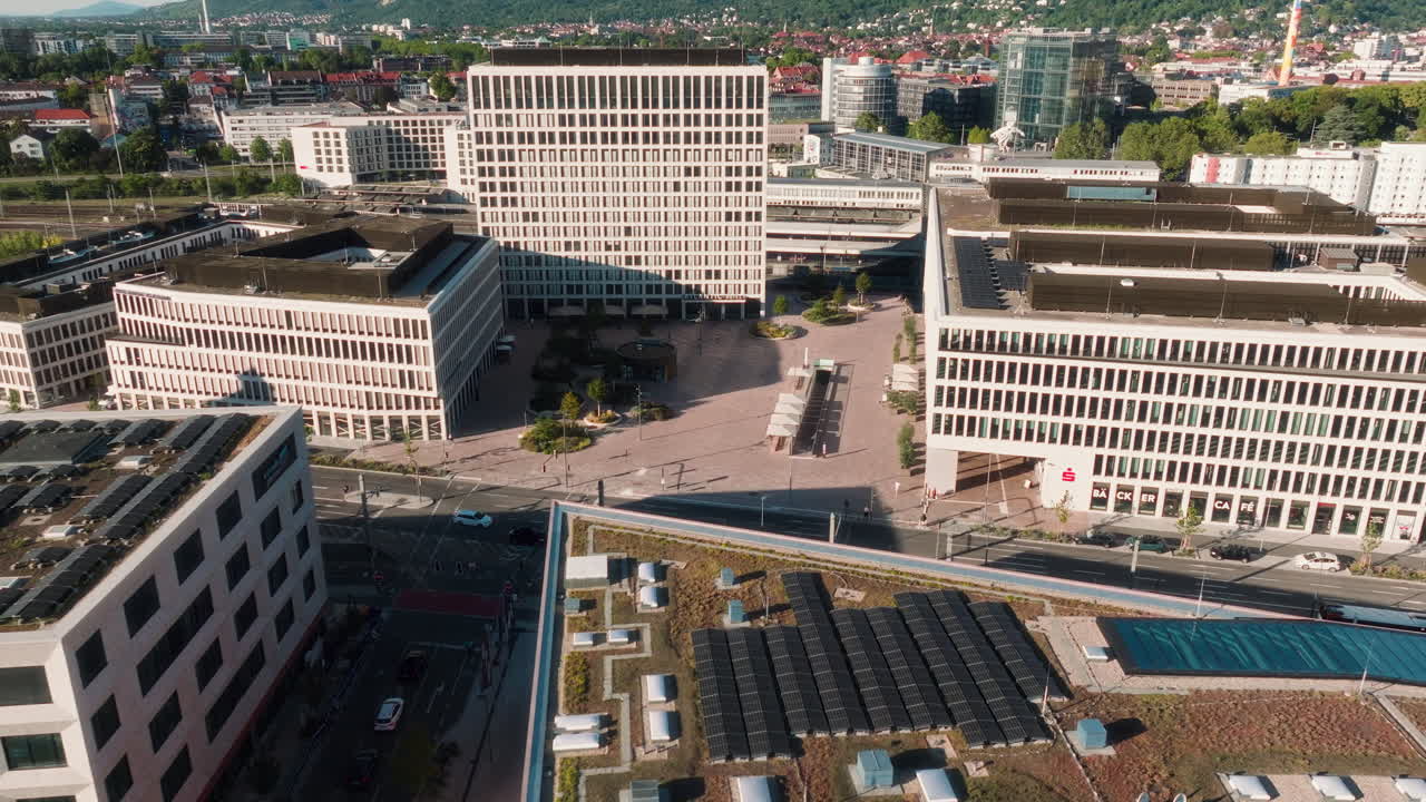 Dynamic drone arc descent past solar-roof building toward Atlantic Hotel and railway district