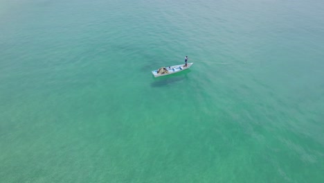 A-guy-fishing-from-a-boat-aerial-view-360-pan-on-the-tropical-island-of-Tobago-in-the-Caribbean