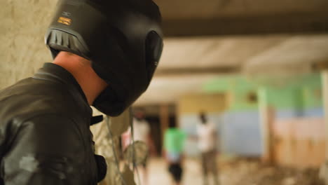 person in helmet looks at criminals and hostage in building