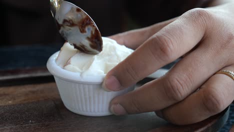 persona comiendo helado con salsa de chocolate