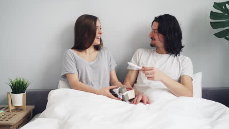 couple surprised with a gift in bed