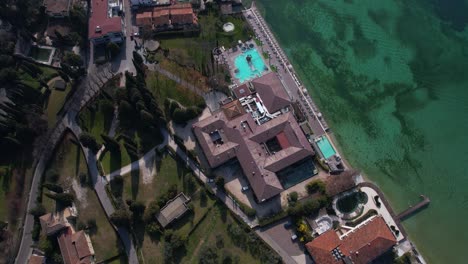 Vista-Aérea-De-Pájaro-Del-Complejo-Hotelero-En-La-Costa-Del-Lago-De-Garda,-Sirmione,-Lombardía,-Italia