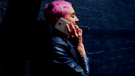 mujer de cabello rosa hablando por teléfono móvil en el callejón 4k