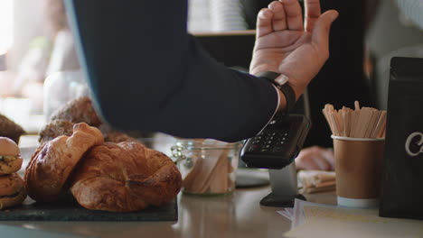 close up customer making contactless payment using smart watch mobile money transfer spending money in cafe with digital transaction service technology