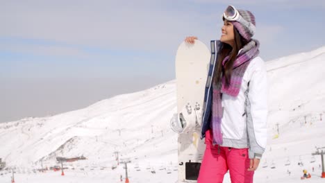 Smiling-gorgeous-woman-posing-with-her-snowboard