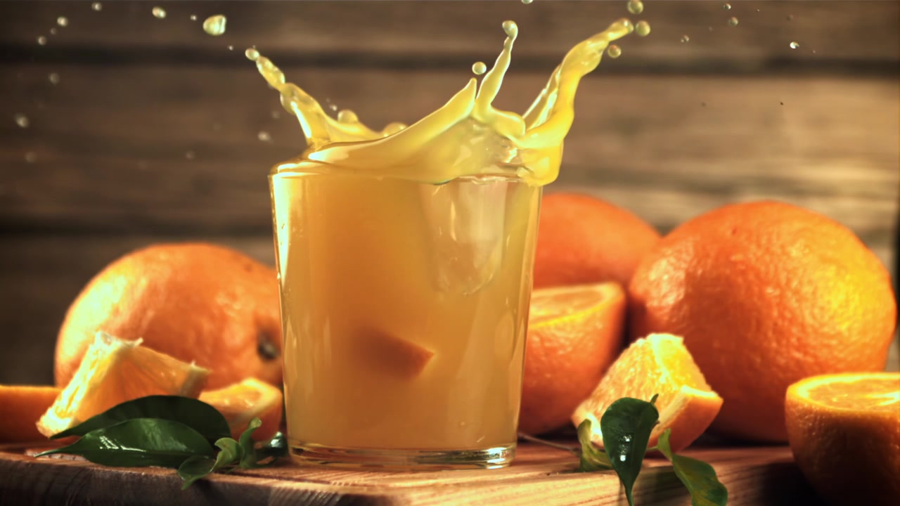 Slow Motion Orange Slice Splashing into Fresh Orange Juice