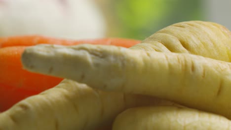 close up of unpeeled parsnips with carrots in background in natural light ready to peel and cook. healthy nutritional organic vegetables.