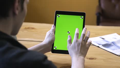 person holding a tablet with a green screen