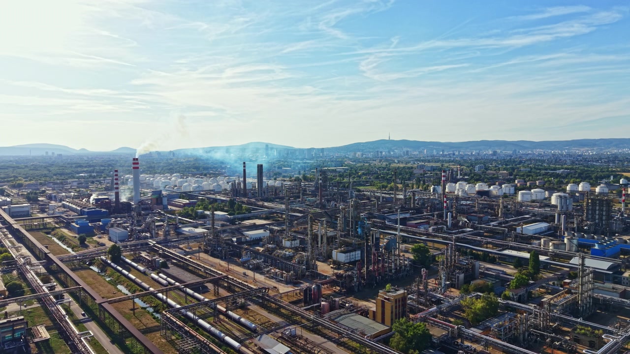 Factory complex in an industrial area with smoke and machinery visible