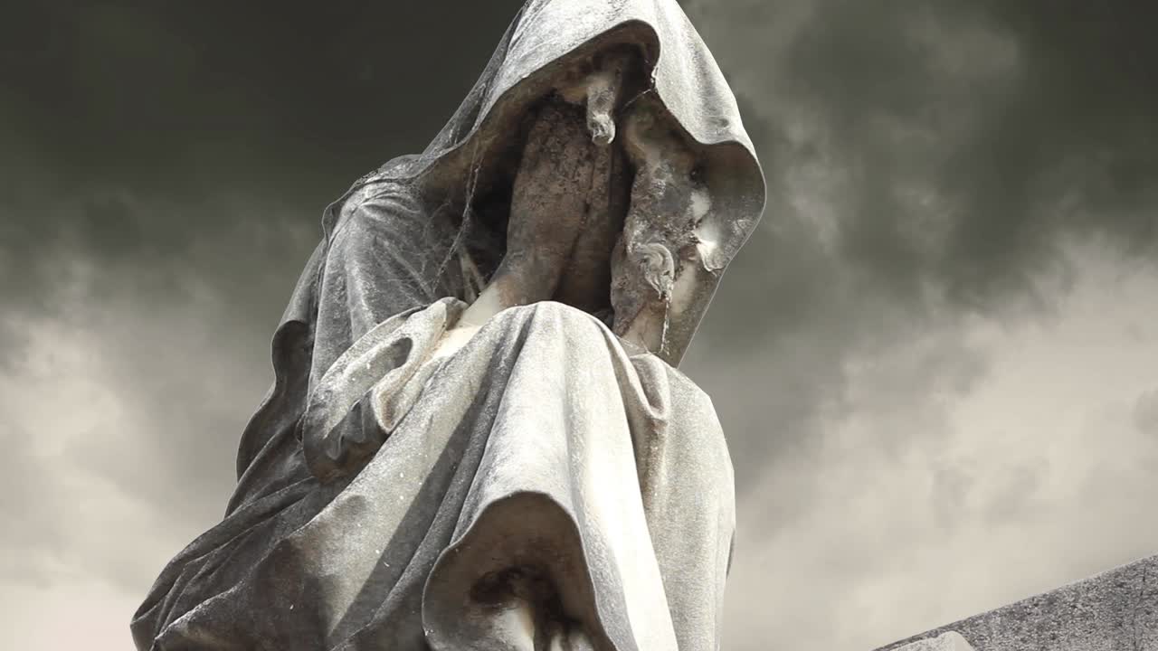 Malinconica statua di pietra di una figura incappucciata in lutto