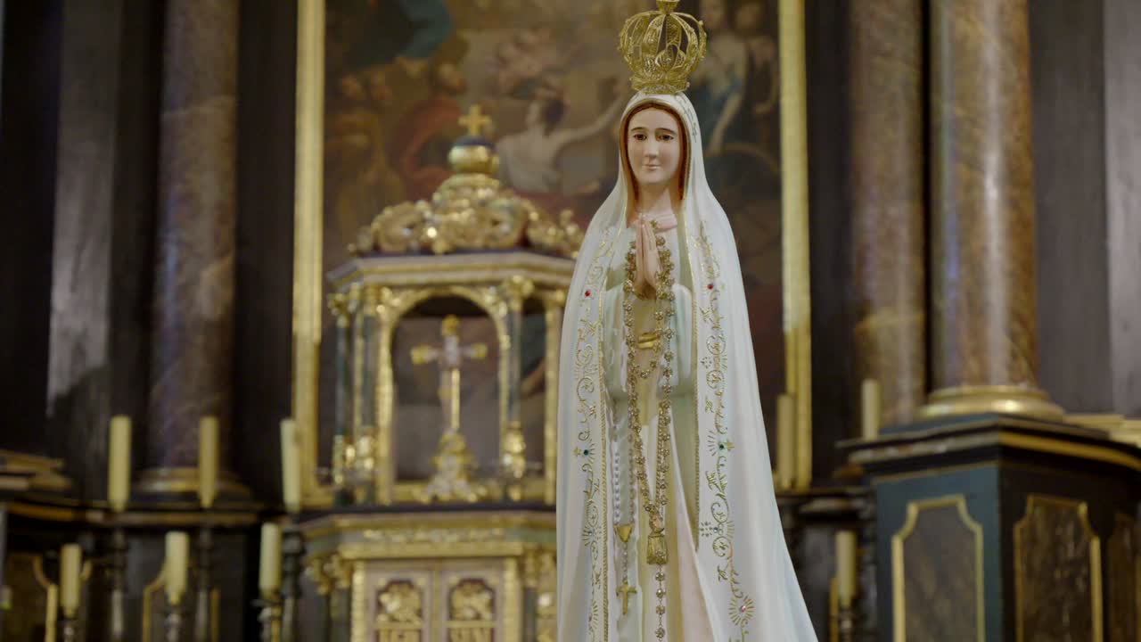 Estátua da Virgem Maria em igreja com sacrário no plano de fundo