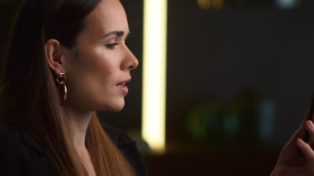 mujer de negocios seria hablando en video chat en el teléfono móvil en la oficina de casa