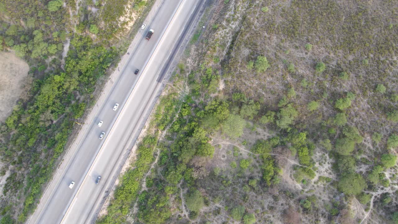 view from above showing vehicles traveling along a highway surrounded by green vegetation in Pakistan