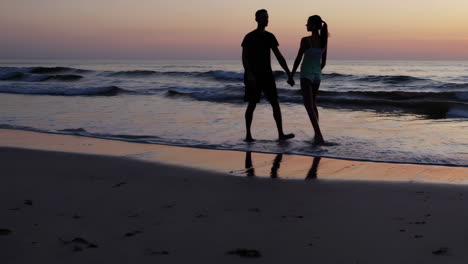 couple walking on the beach at sunset