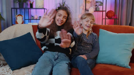 siblings children girls smiling friendly at camera, waving hands gesturing hello hi greeting goodbye