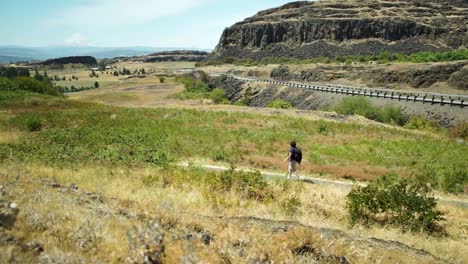 a lone mature woman day hiker walking along the trail at horse thief butte state park, washington