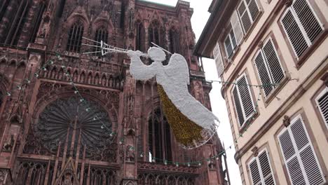 angel christmas decoration floating above european streets in front of strasbourg cathedral at a festive christmas market in europe