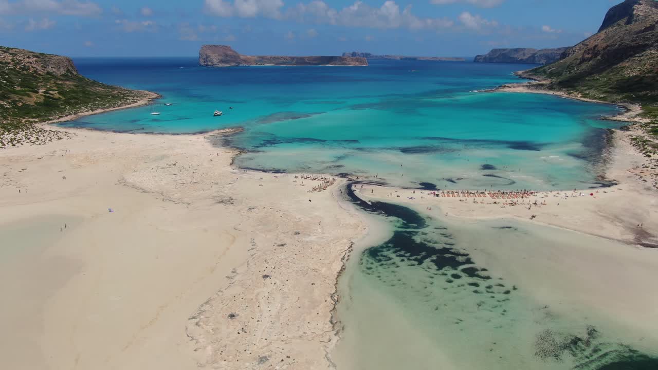 Saltwater lagoon in Balos Beach on Crete Greece with bathing tourists below right, Aerial dolly in shot