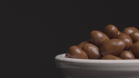 disparo de cerca de un cuenco giratorio de cacahuetes cubiertos de chocolate