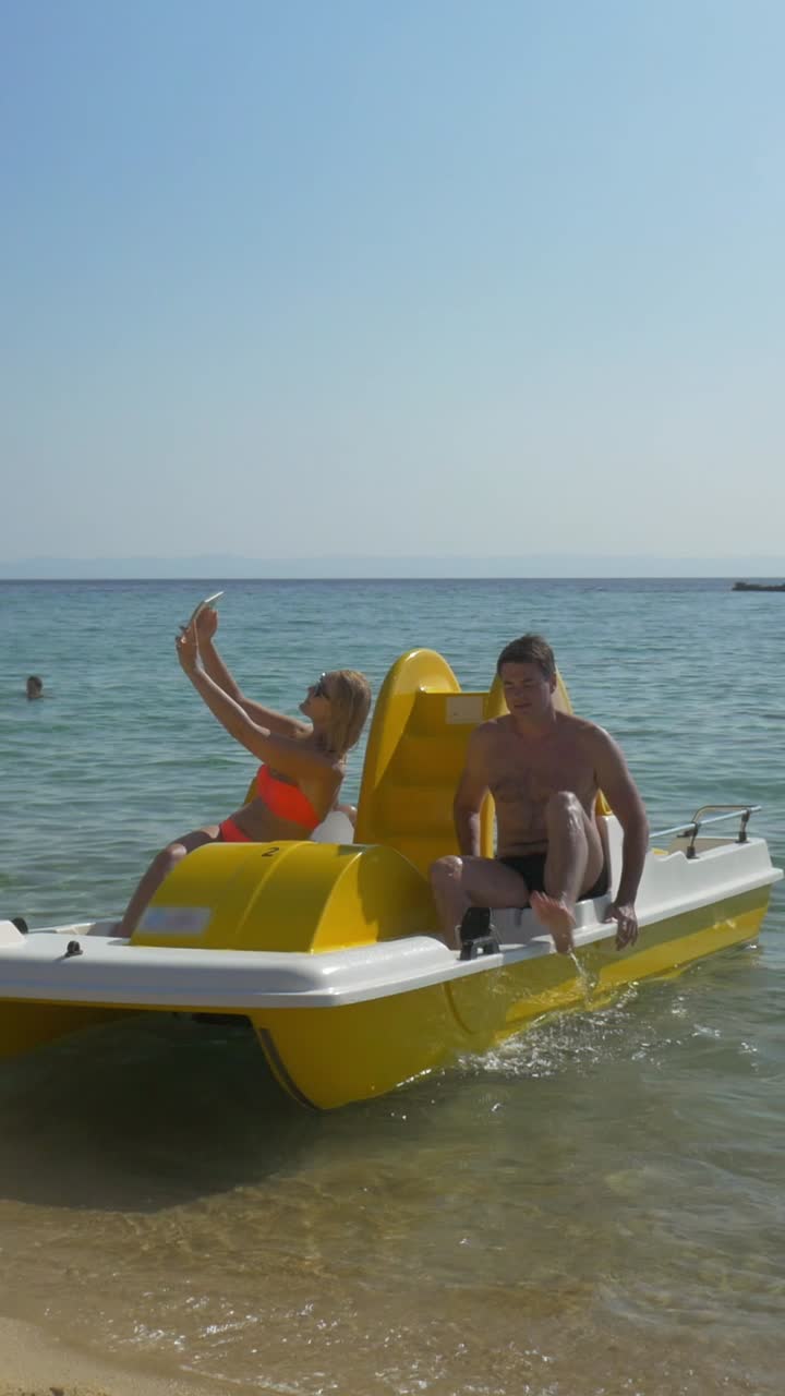 Famiglia su un pedalò che si scatta un selfie su una spiaggia soleggiata