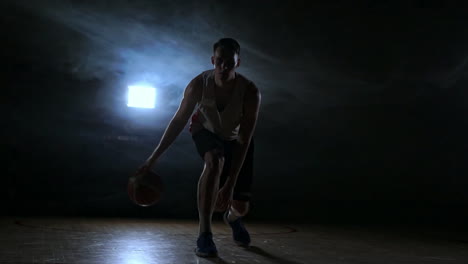 one young adult man, basketball player dribble ball, dark indoors basketball court. slow motion