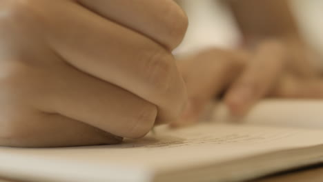 close up of hand holding a pen and writing on a notebook