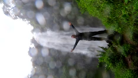 man shouting and raising arms at the base of materuni waterfall