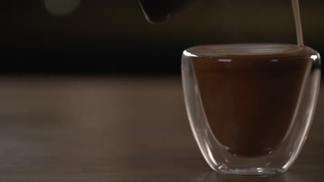 Milk-being-poured-into-a-small-glass-of-liquid-chocolate