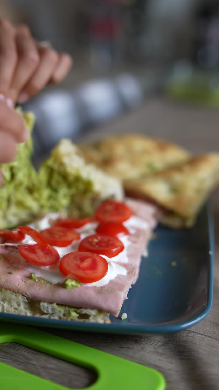 preparando sándwiches de foccacia con jamón y tomates