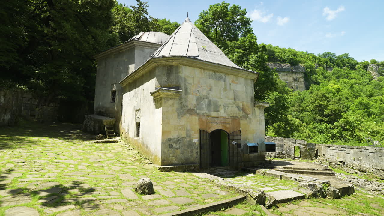 Panning from the left to the right showing the front yard and the mausoleum of the Alevian saint Demir Baba Teke surrounded by a forested area in Isperih, in the province of Razgrad, in Bulgaria.