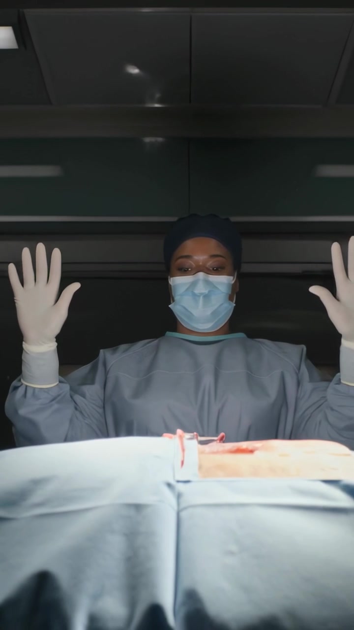 Vertical video: Raising gloved hands after incision sterile check, masked surgeon over drape clamp