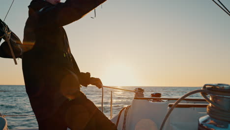 sunset, boat and man pull anchor at ocean to