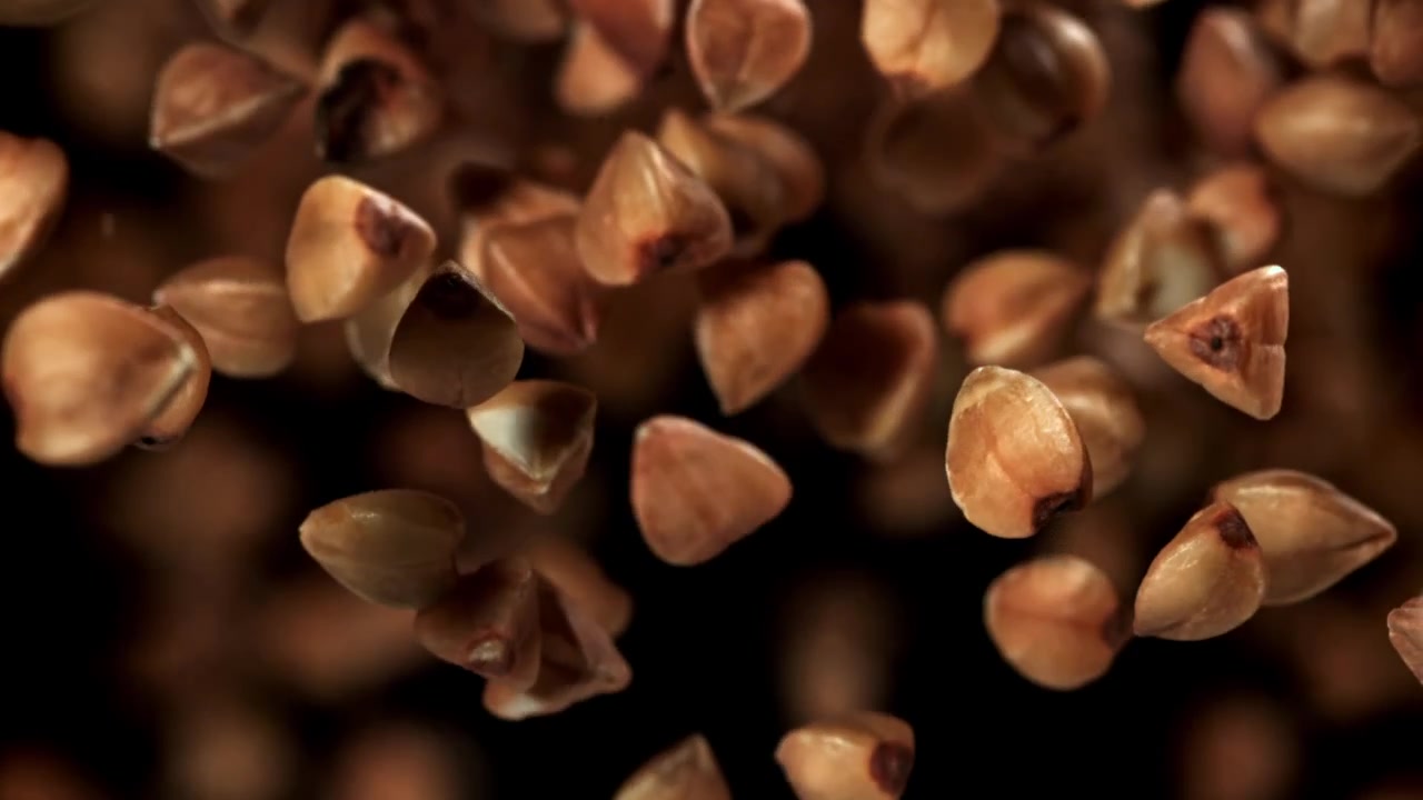 Raw Buckwheat Groats Falling in Slow Motion Against Black Background