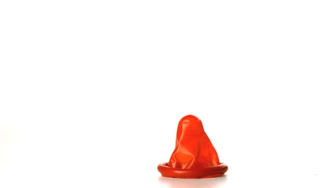 Red-condom-falling-on-white-background