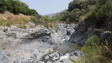 un rayo constante de agua del río que corre entre las montañas en taormina, italia