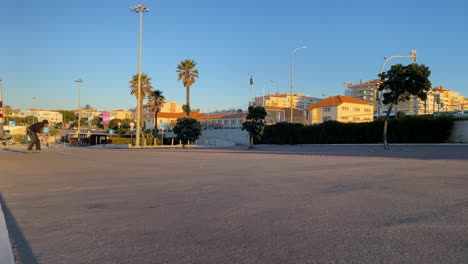 super slow motion of attractive male skater with black sweater generating speed on a skateboard with the first rays of the sun in a beach park