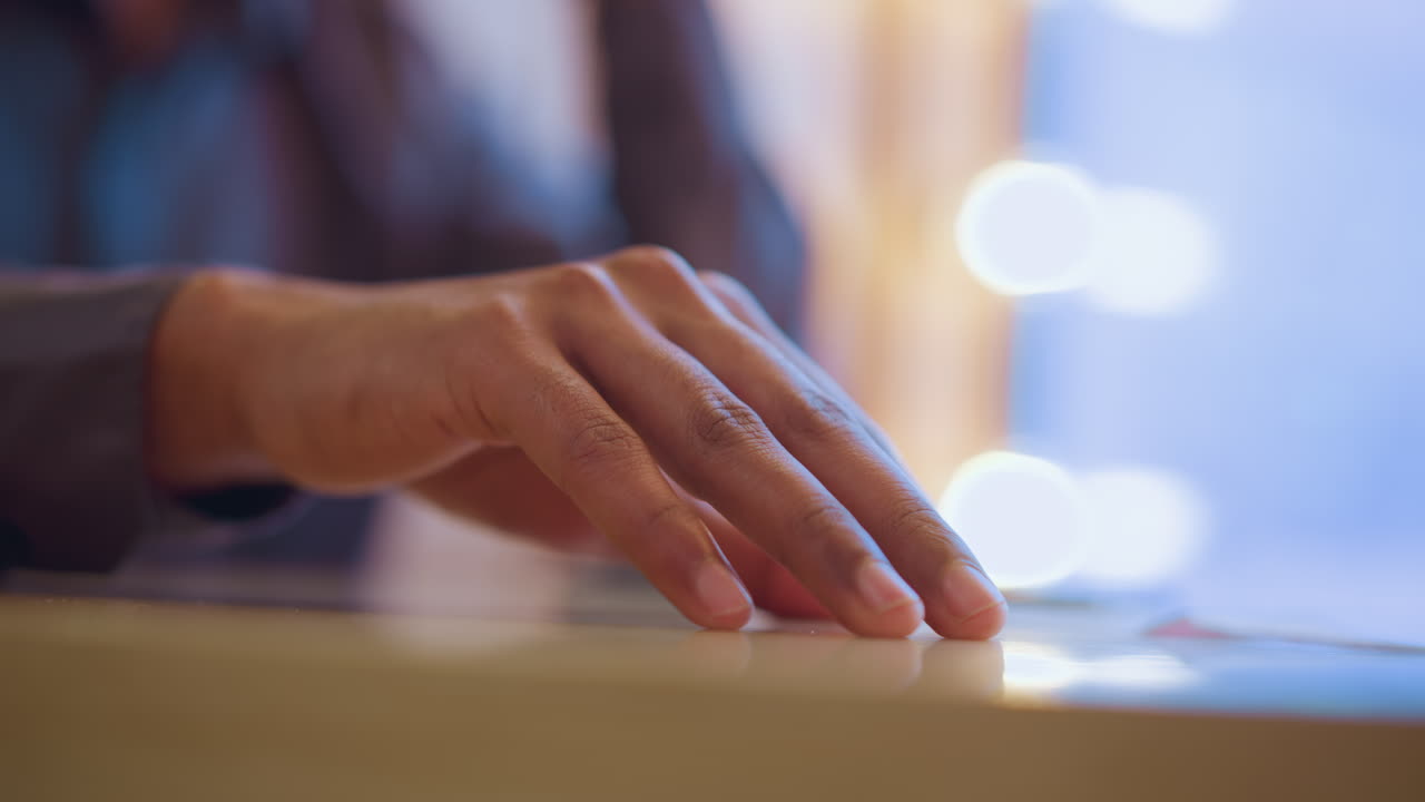 Close-up of young man's hand resting gently on light wooden table beside napkin in soft daylight, fingers slightly apart, conveying mood of stillness, mindfulness, and calm presence in indoor quiet setting