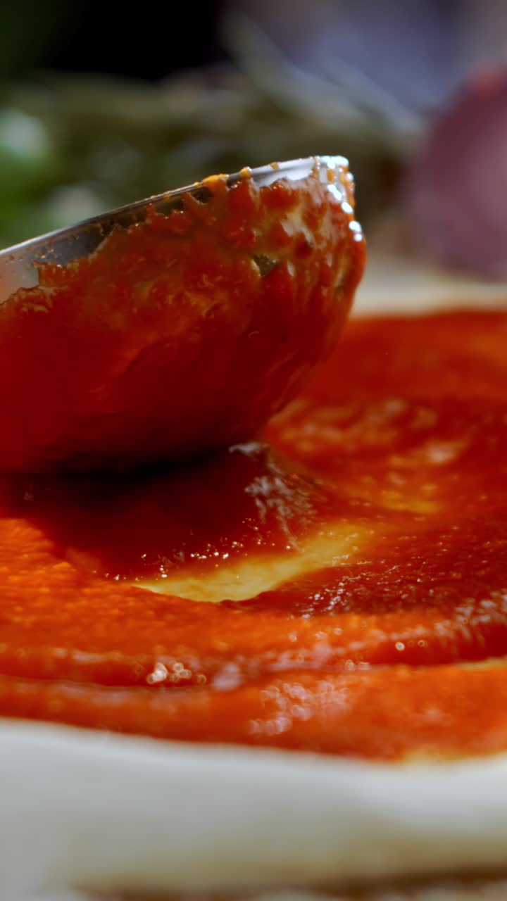 Pizza sauce being spread on dough