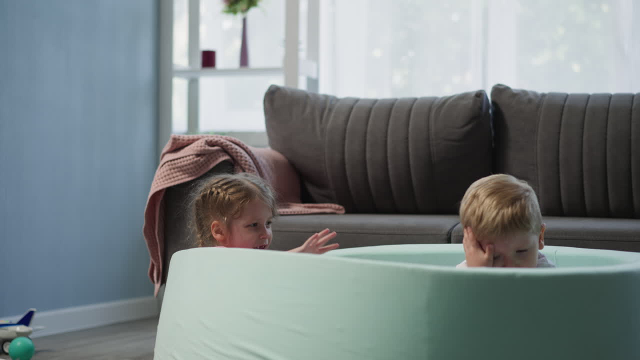 미소 짓는 유치원 소녀 가 유아 소년 에게 플라스틱 공 을 던진다