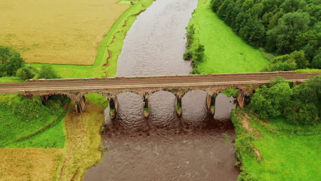 Toma-Aérea-Que-Sigue-Hacia-Atrás-Mirando-Un-Viaducto-Ferroviario-Que-Cruza-Un-Río,-Manteniendo-El-Viaducto-En-El-Centro-Del-Marco