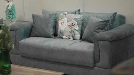 close-up of grey couch decorated with christmas pillow and seasonal ornaments in living room.
