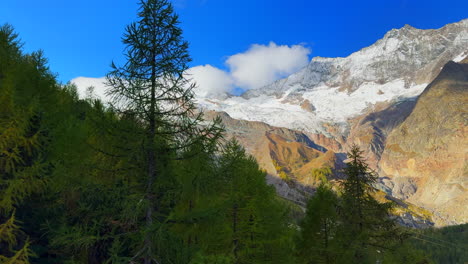 Larks-forest-Saastal-Saas-Fee-Switzerland-chairlift-ride-top-of-Swiss-Alps-glacier-mountain-peaks-summer-fall-autumn-morning-stunning-vibrant-blue-sky-alpine-valley-Zermatt-Alphabel-pan-left