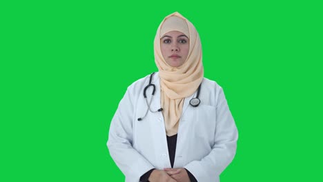 serious muslim doctor looking at the camera green screen