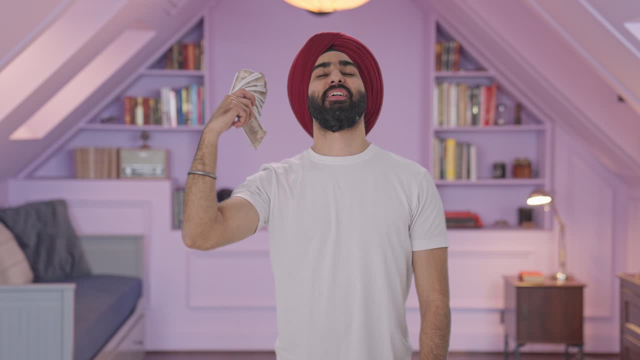 hombre indio sikh feliz usando dinero como ventilador