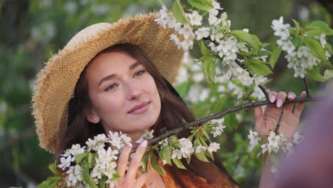 Atractiva-Dama-De-Ojos-Verdes-Con-Sombrero-De-Paja-Huele-Un-Retrato-De-Rama-De-Cerezo-En-Flor