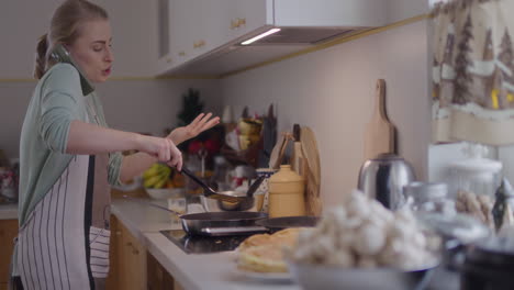 upset woman working in the kitchen talking on the phone and getting upset while cooking