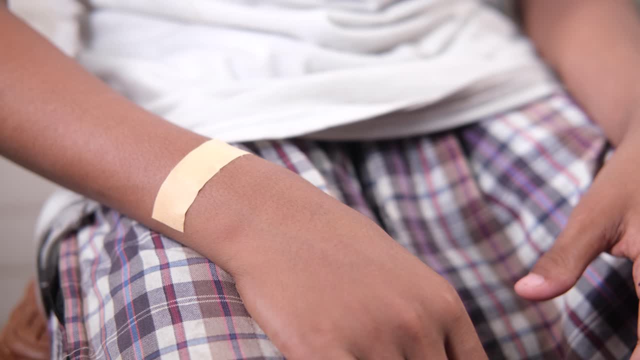 niño adolescente poniendo vendajes adhesivos en la mano,